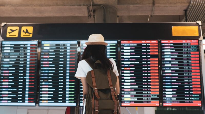 paro de aeropuertos: pasajera mira el tablero de vuelos con su valija