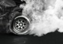 sanción a Colapinto: auto de carreras con humo en las ruedas sobre fondo oscuro