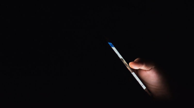 mano con un celular iluminado en la oscuridad, desnudos con IA
