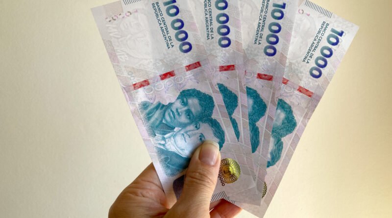 manos sosteniendo billetes de 10.000 pesos argentinos, jubilaciones de octubre