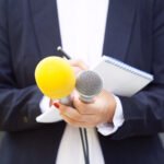 Luck Ra: periodista con micrófono en una conferencia de prensa
