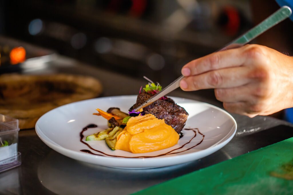 MasterChef Celebrity: manos de chef emplatando un plato gourmet