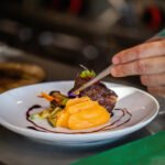 MasterChef Celebrity: manos de chef emplatando un plato gourmet