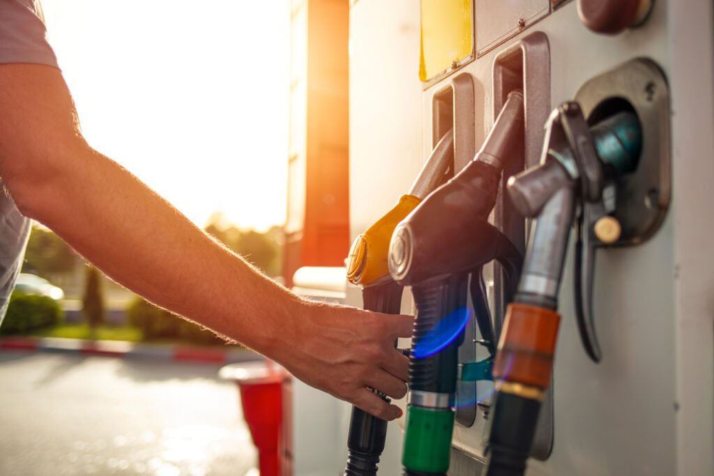 mano sosteniendo un surtidor de combustible, precios de la nafta