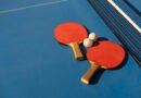tenis de mesa: paletas y pelota blanca sobre una mesa de ping pong azul