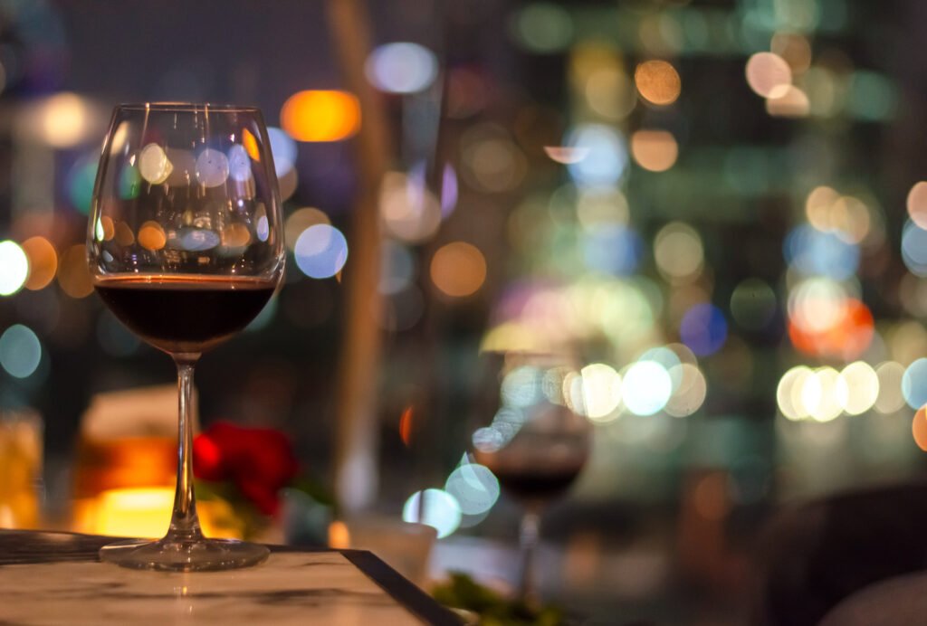 copa de vino con luces de la ciudad de fondo, Zaira Nara